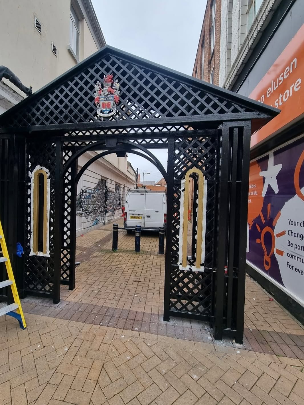Ornate timber lattice archway freshly painted in black gloss on a UK high street