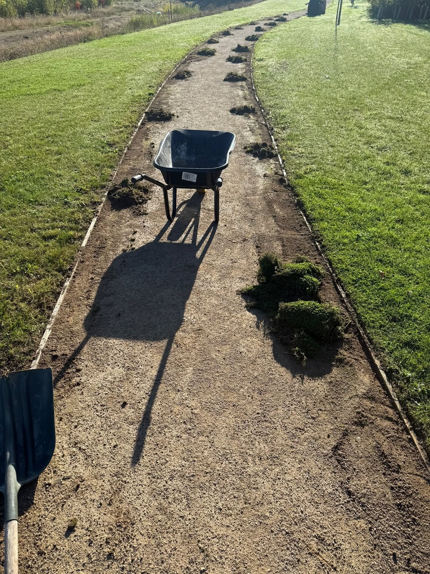 Path edge being prepared with wheelbarrow and grass clippings
