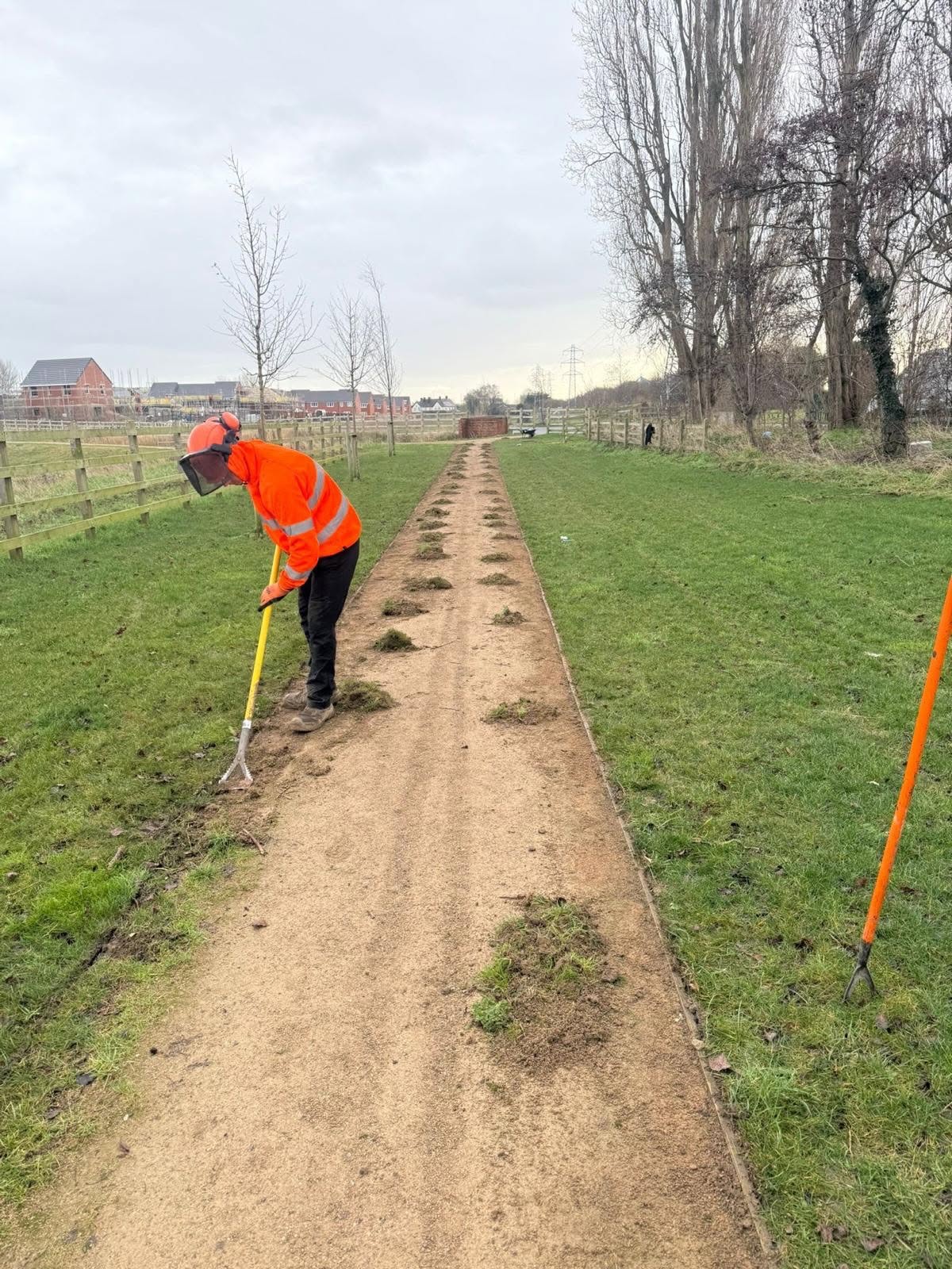 DMS operative raking back overgrown footpath edges before redressing