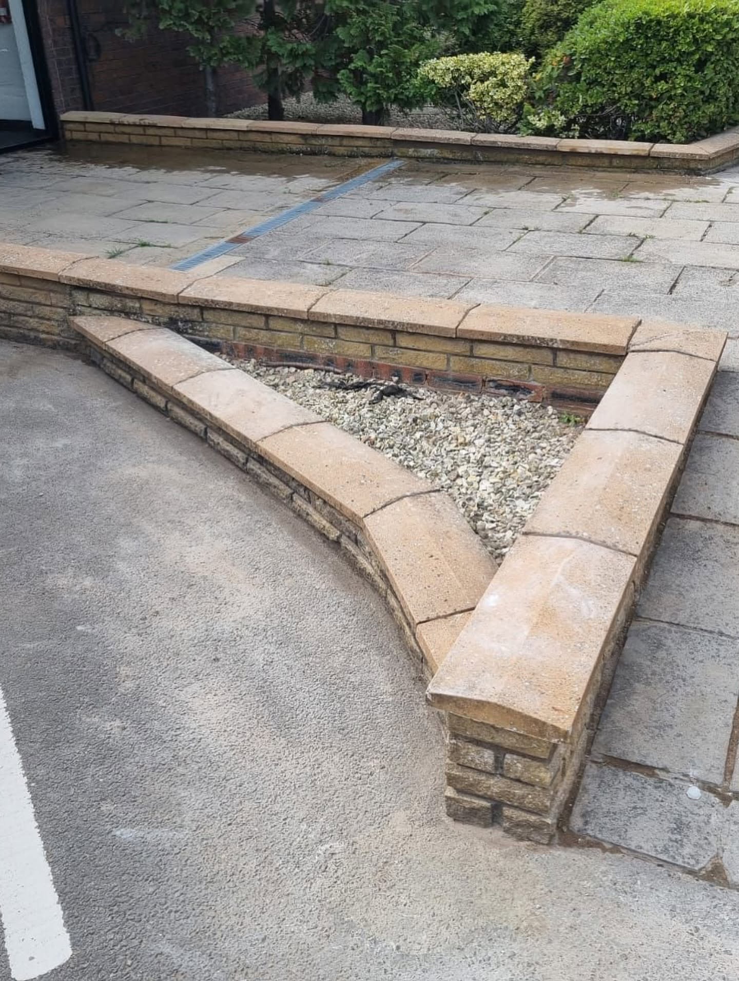 Brick planter filled with gravel in a tidy paved courtyard