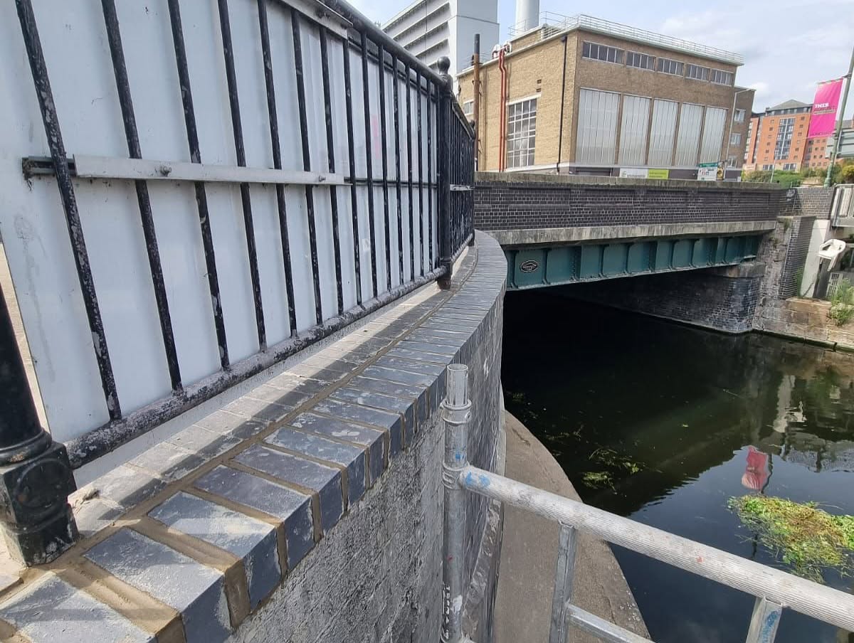 Cleaned brickwork and railing border overlooking a waterway