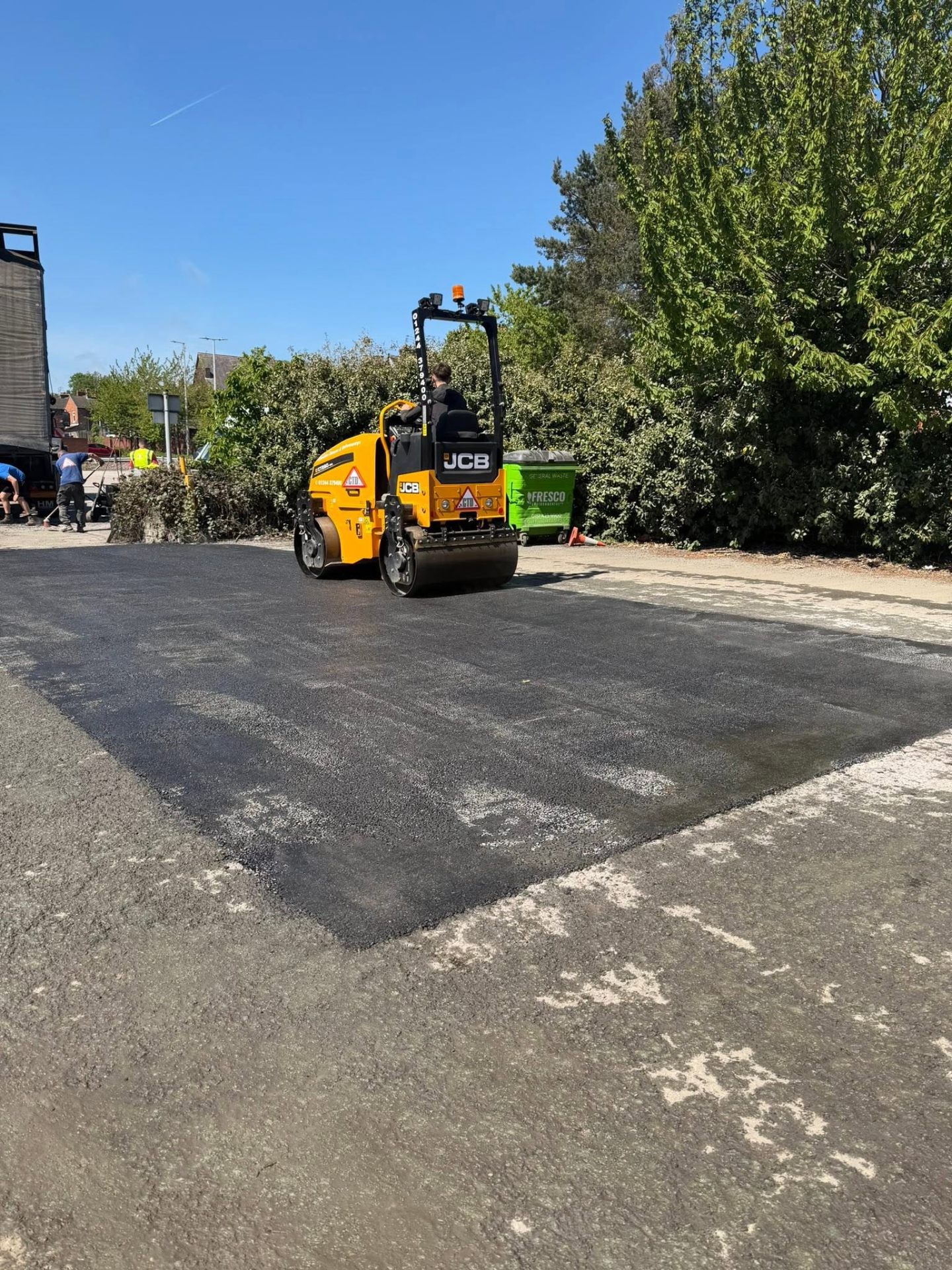 Vibratory roller compacting freshly laid tarmac on a driveway