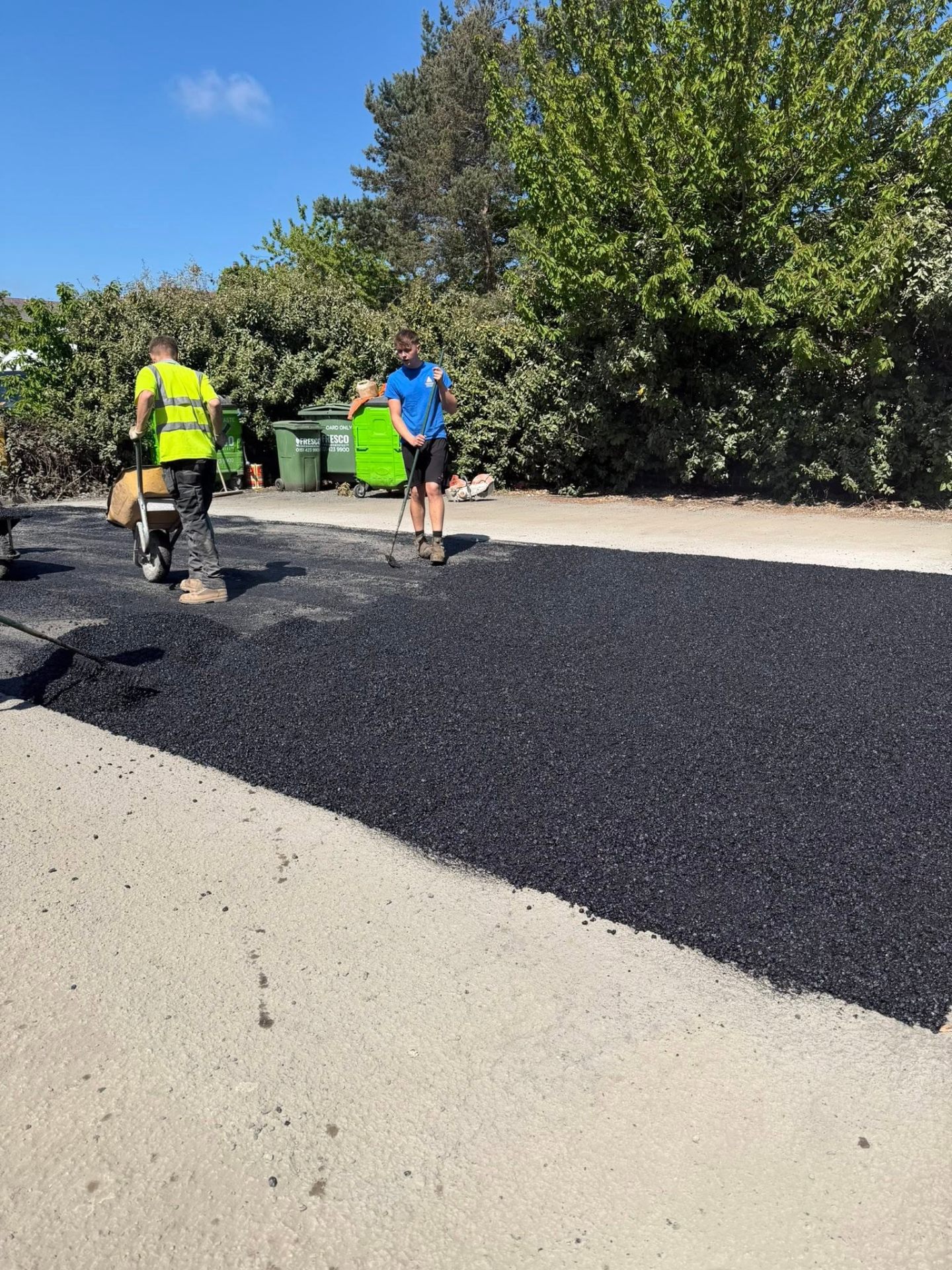 Fresh asphalt being laid and levelled on a driveway surface