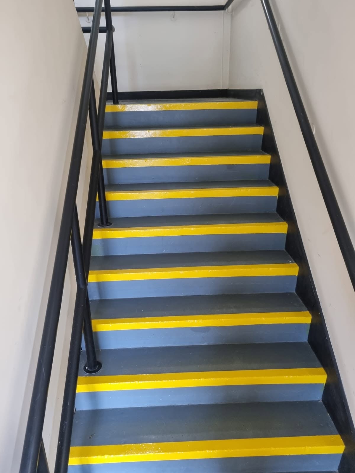 Communal concrete stairs freshly painted with high-visibility yellow nosings