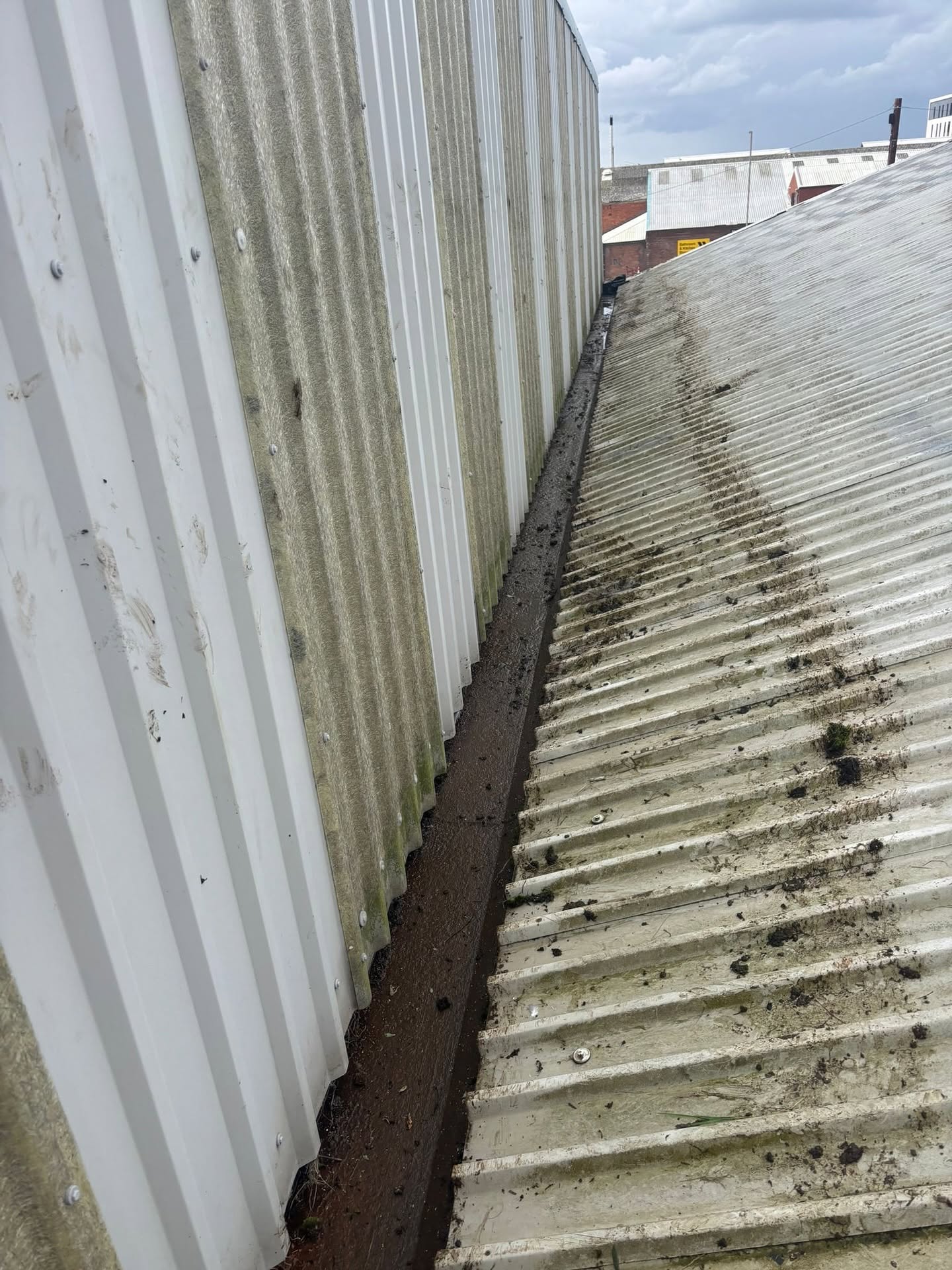 Industrial valley gutter cleared of accumulated debris during roof maintenance
