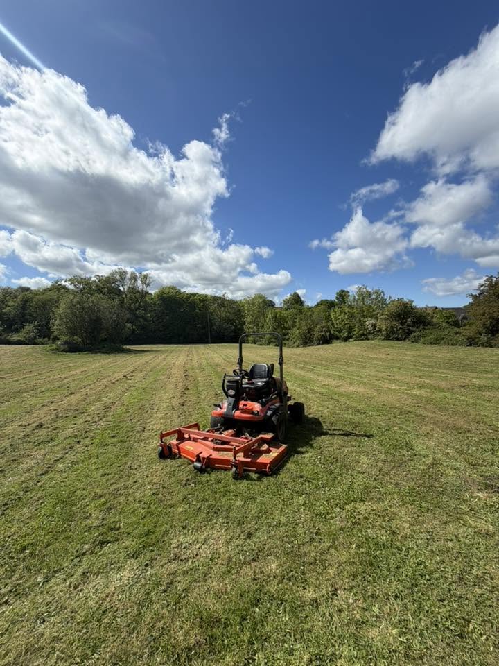 Ride-on mower cutting open grassland on a North Wales grounds maintenance contract